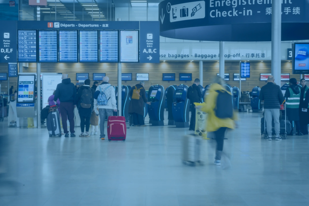 Self‑service check‑in kiosks in an airport hall with passengers.