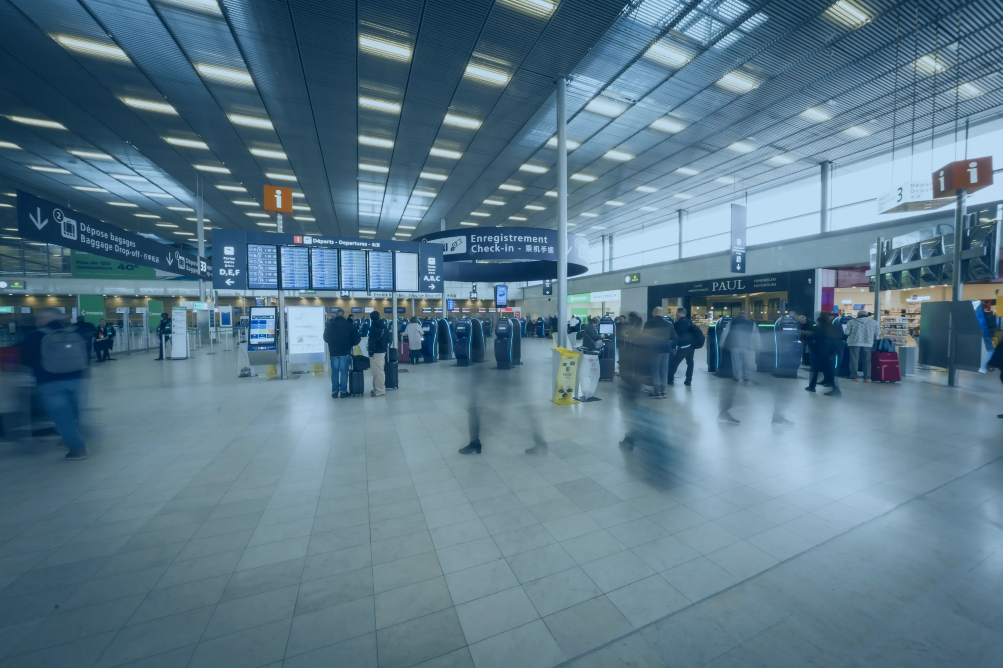Hall d’aéroport avec voyageurs, bornes d’enregistrement et panneaux d’informations pour la gestion des flux.